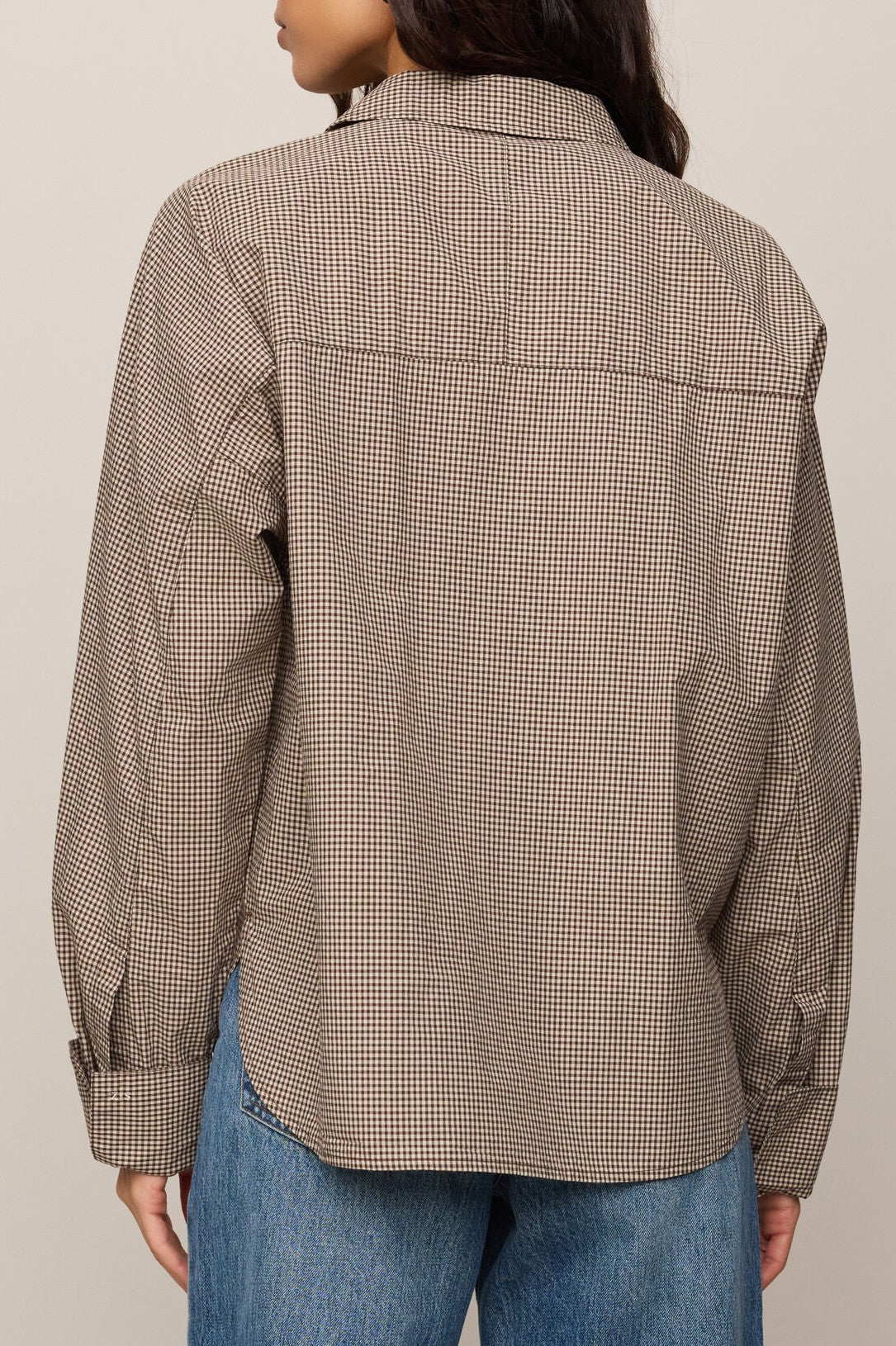 A person shown from the back wearing the Z Supply On Duty Gingham Button Up—a brown and white plaid, collared button-front shirt—paired with blue jeans.