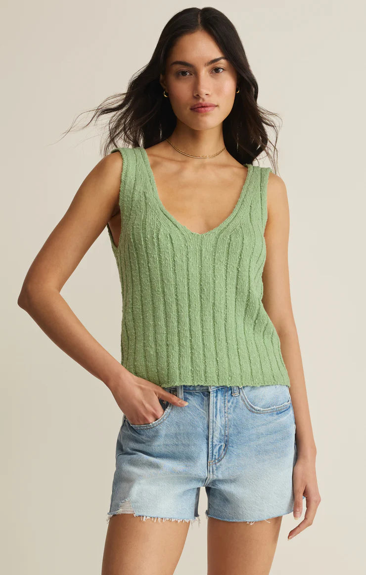 A woman models the Z Supply Acadia Sweater Tank in green, paired with light blue denim shorts. She stands against a plain background with one hand in her pocket.