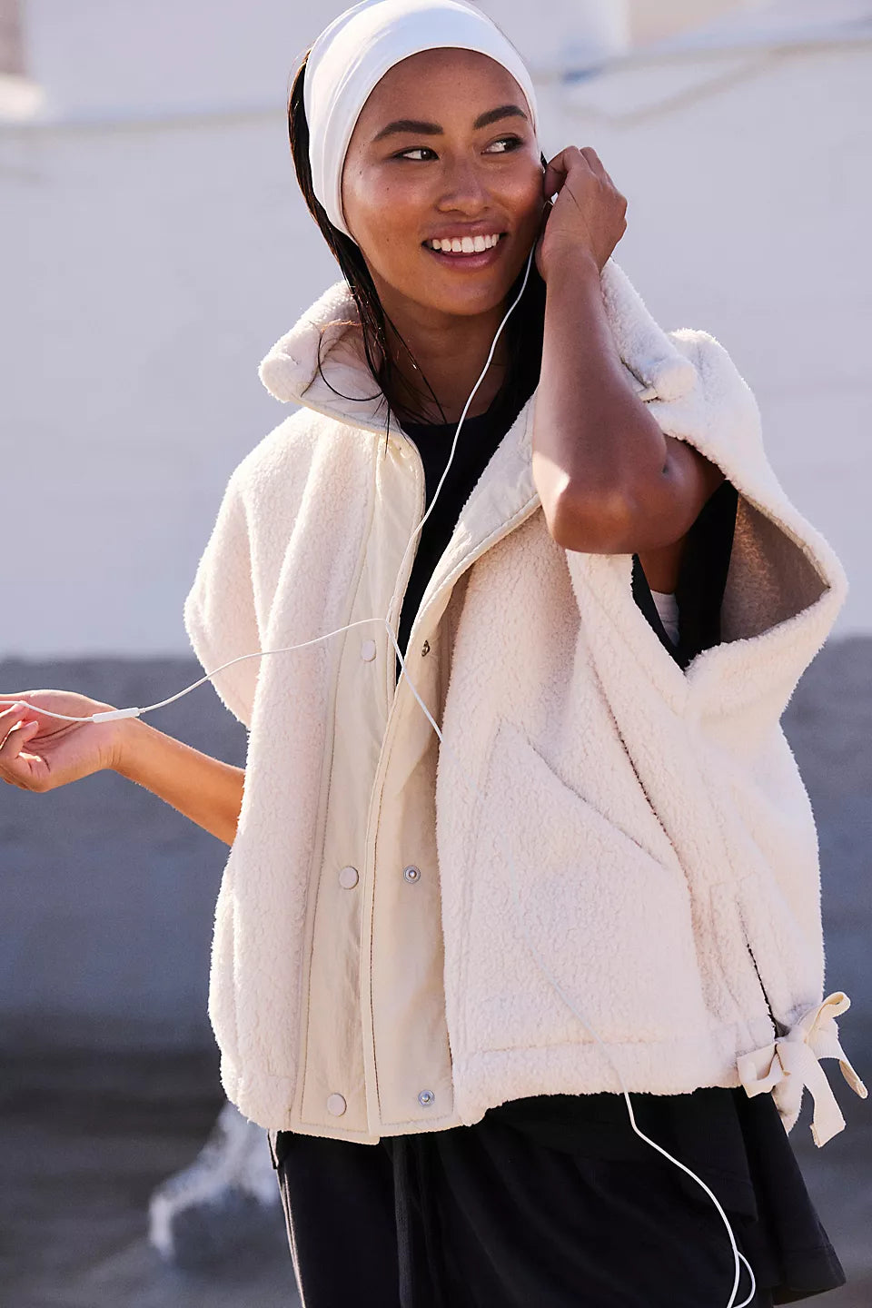 Cream-colored quilted vest with button front and side ties, worn over black shirt.