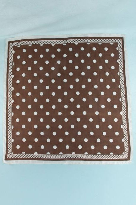 The Polka Dot Scarf by South Moon Under, crafted from soft polyester in brown satin with white polka dots and a crisp white border, is displayed flat on a light blue surface.