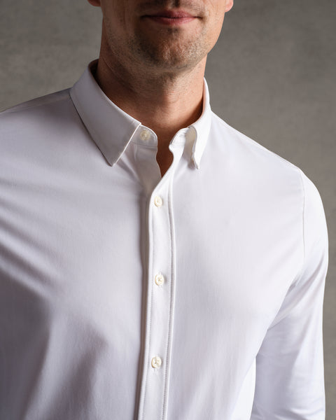 A man wears the RHONE Commuter Shirt- Classic Fit, collar visible, shown from shoulders to mid-chest against a neutral gray background.