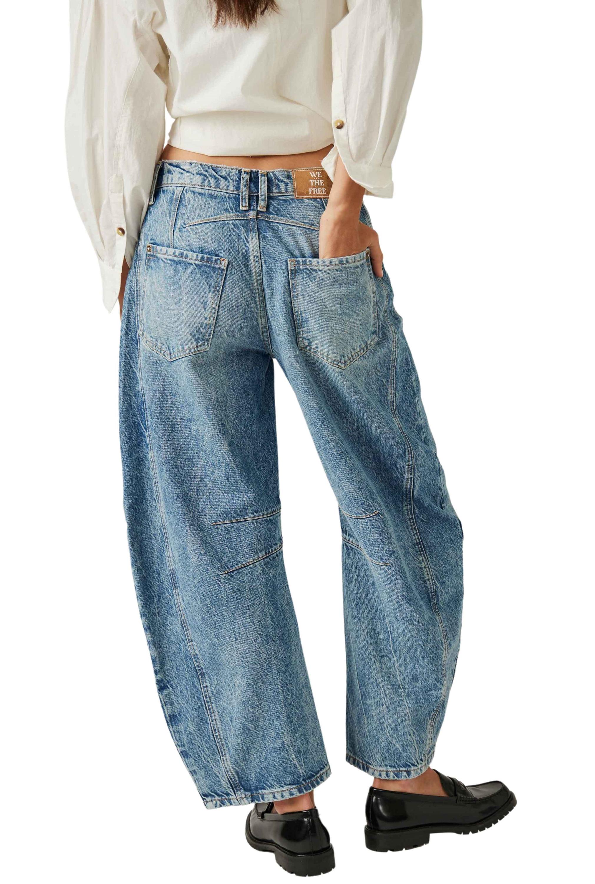 A person shown from the back wears a white long-sleeve shirt, blue Good Luck Mid Rise Barrel jeans by Free People with five pockets including back pockets, and black loafers.