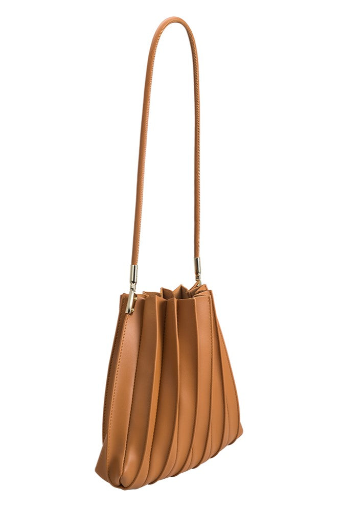 The Melie Bianco Carrie Tan is a premium handbag made from brown vegan leather, featuring a pleated design, gold hardware, and a long shoulder strap, shown against a white background.