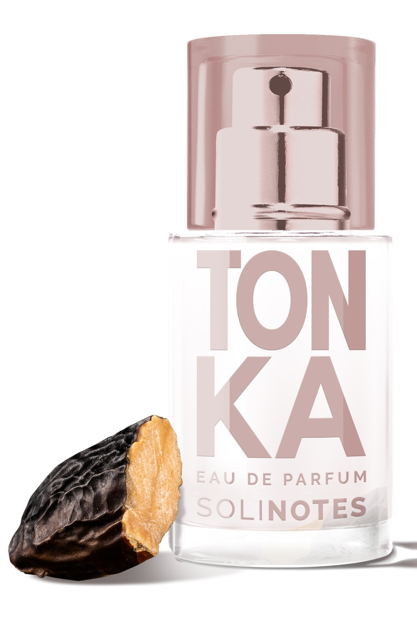 A bottle of Solinotes Mini Tonka 15ml EDP with a metallic spray cap is displayed beside a whole, dark brown tonka bean, partially split to show its lighter inside.