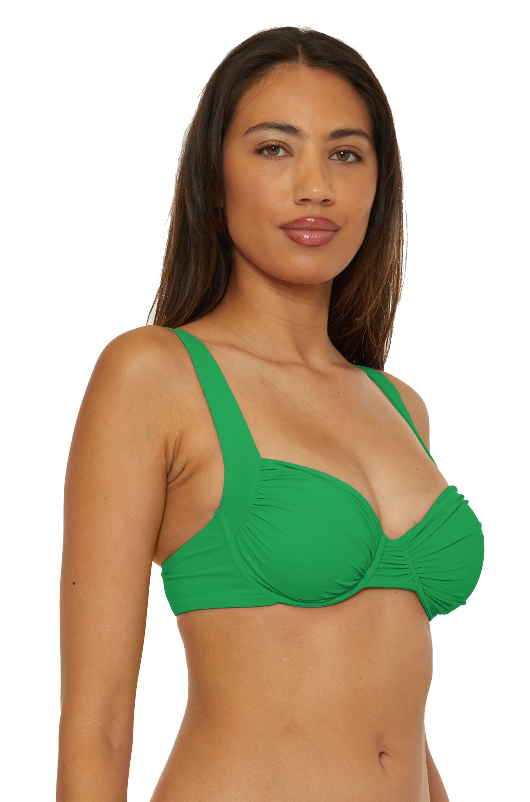 A woman with long brown hair wears the Becca Swim Emerald Color Code Underwire Top, standing against a plain white background and looking forward with a neutral expression.