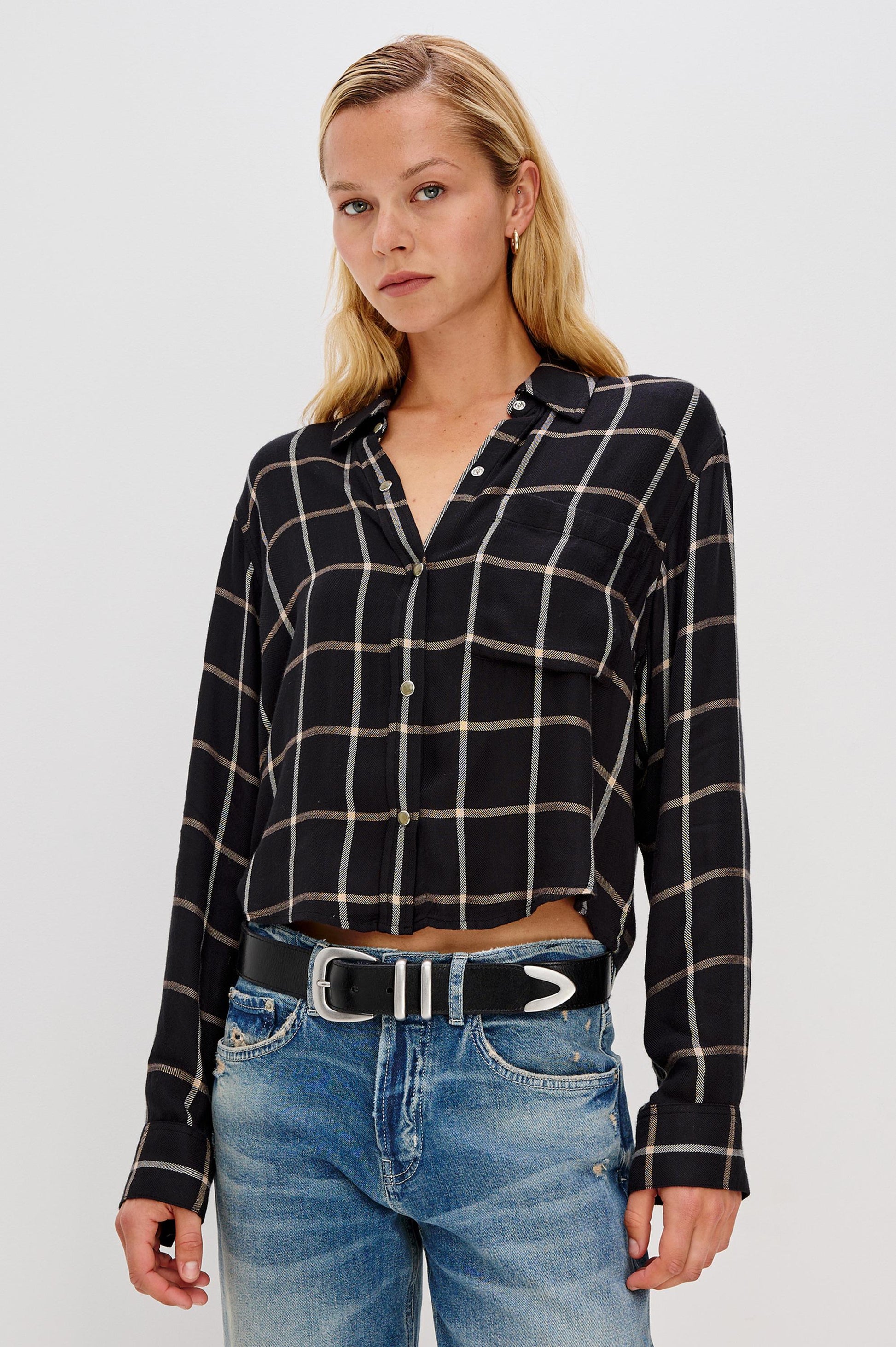 A person with long blonde hair wears the Rails Malin Long Sleeve Check shirt, a black and white plaid button-up in a relaxed fit made of 100% rayon, paired with blue jeans against a plain light background.