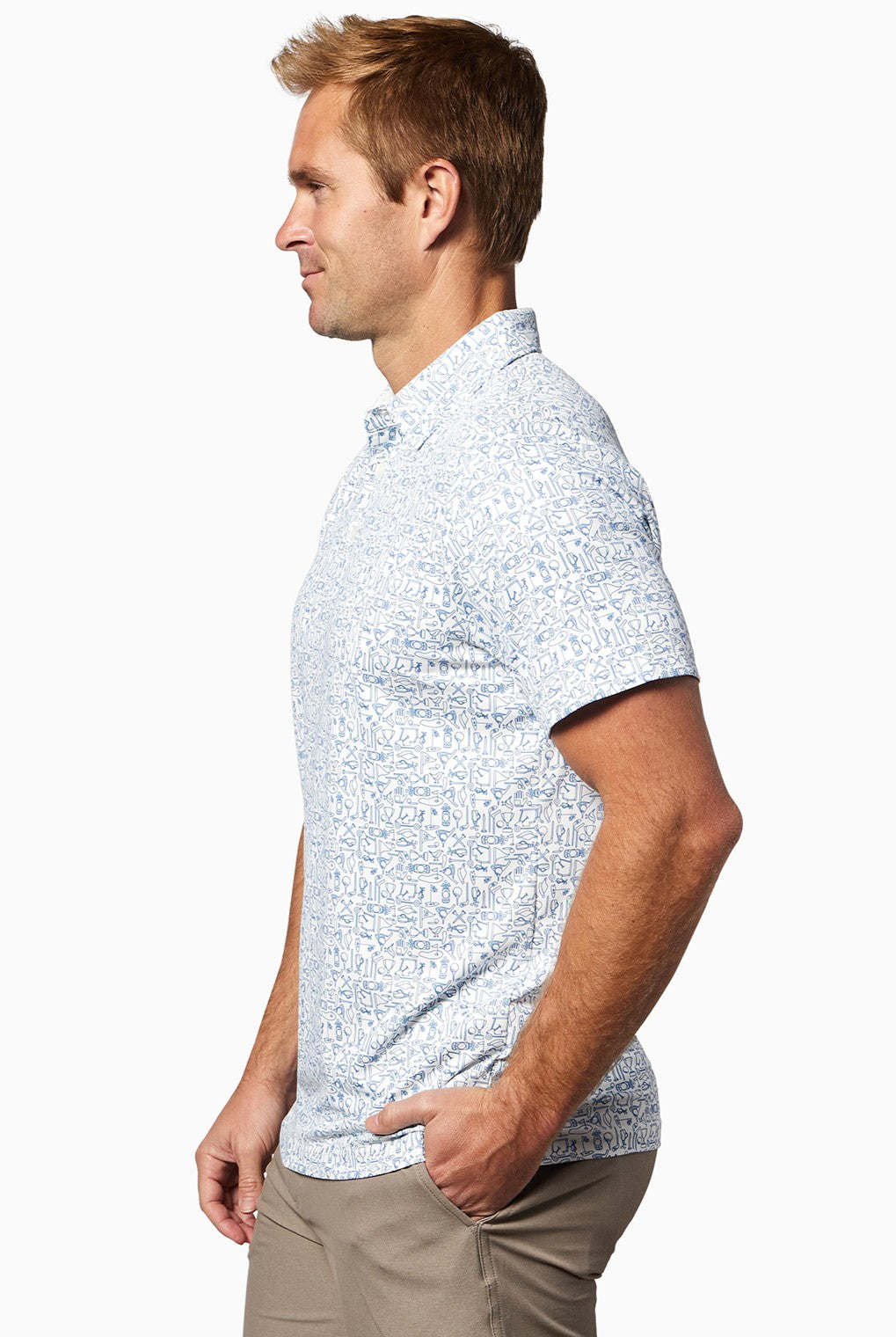 A man with short light brown hair stands sideways, wearing the Toes on the Nose Clubhouse Polo Tequila Therapy in a light blue and white pattern with beige pants against a plain white background.