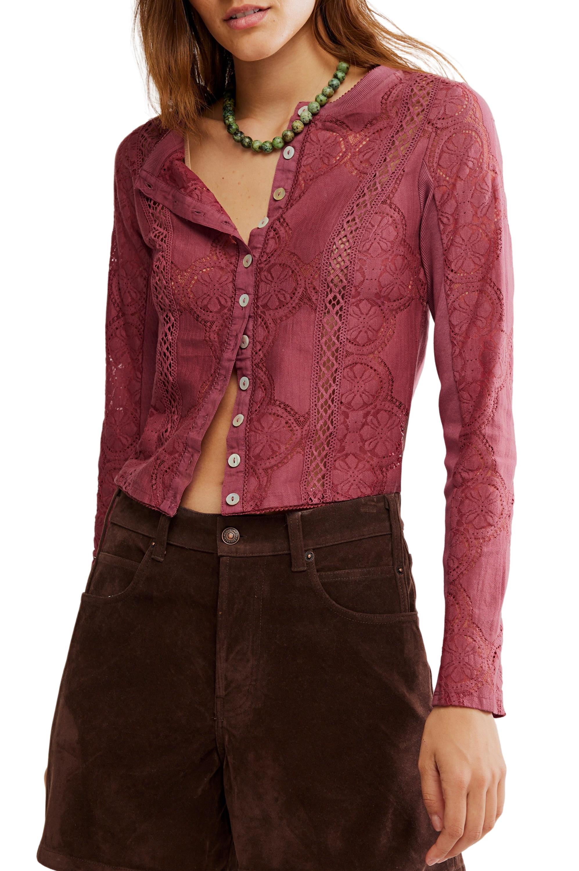 A woman wearing the Free People Jae Knit Long Sleeve top in Crushed Berry, paired with brown shorts and a green beaded necklace. Her face is partially out of the frame.