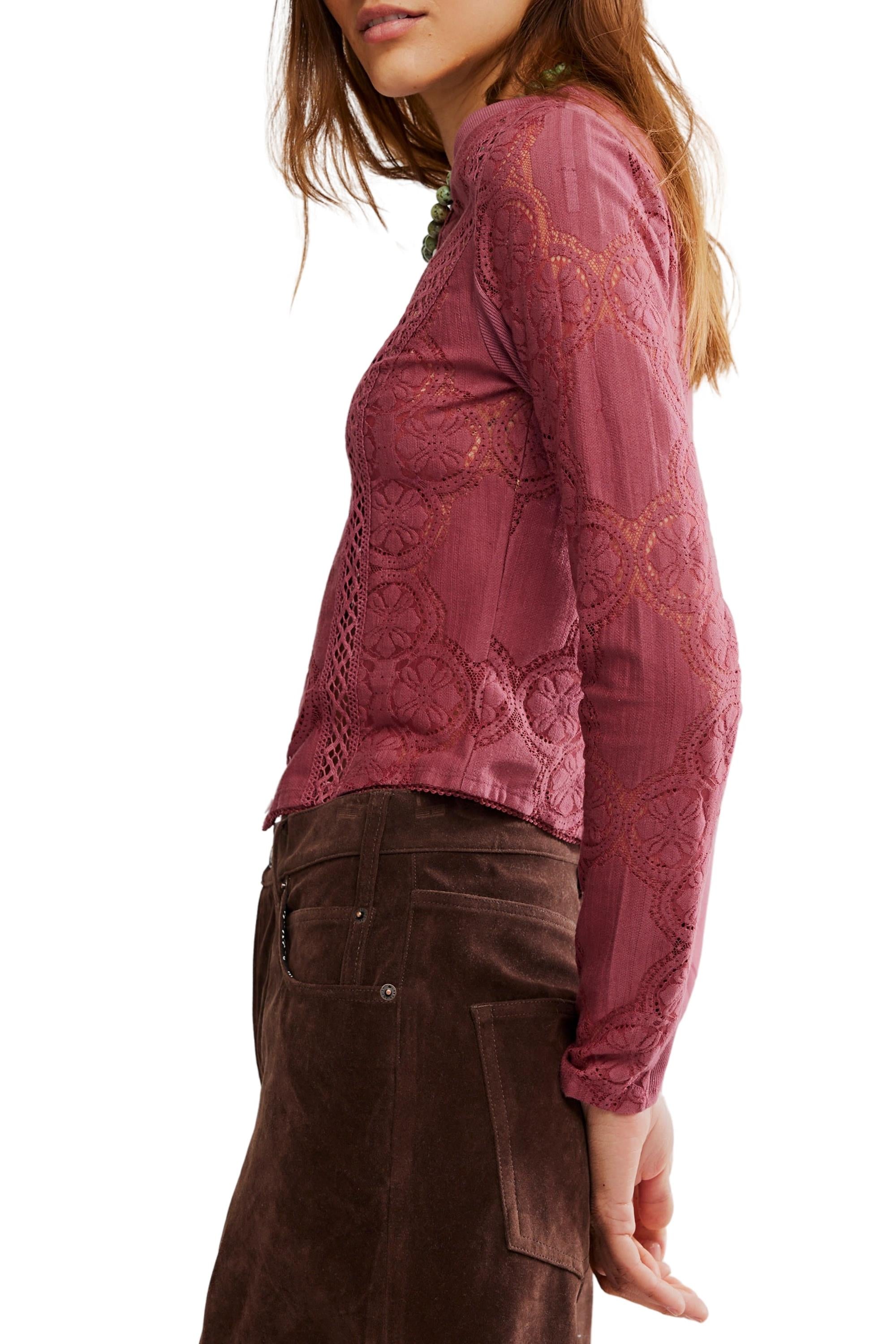 A woman is shown from the side, with her head slightly turned and hair down, wearing the Free People Jae Knit Long Sleeve top in mauve sheer cotton-lace and a brown suede skirt.