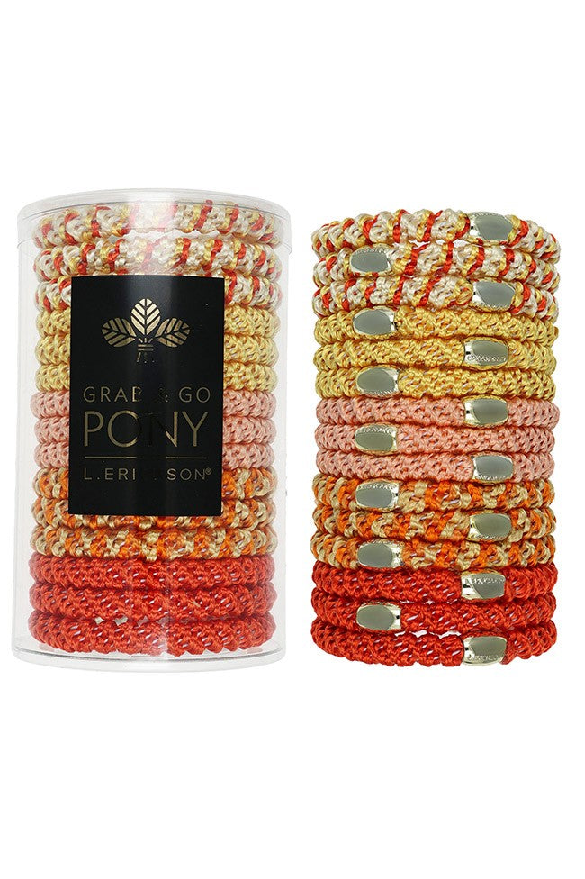 A set of coral braided hair ties from The Finest Accessories' Grab & Go Pony Tube, stacked beside a clear cylindrical container.