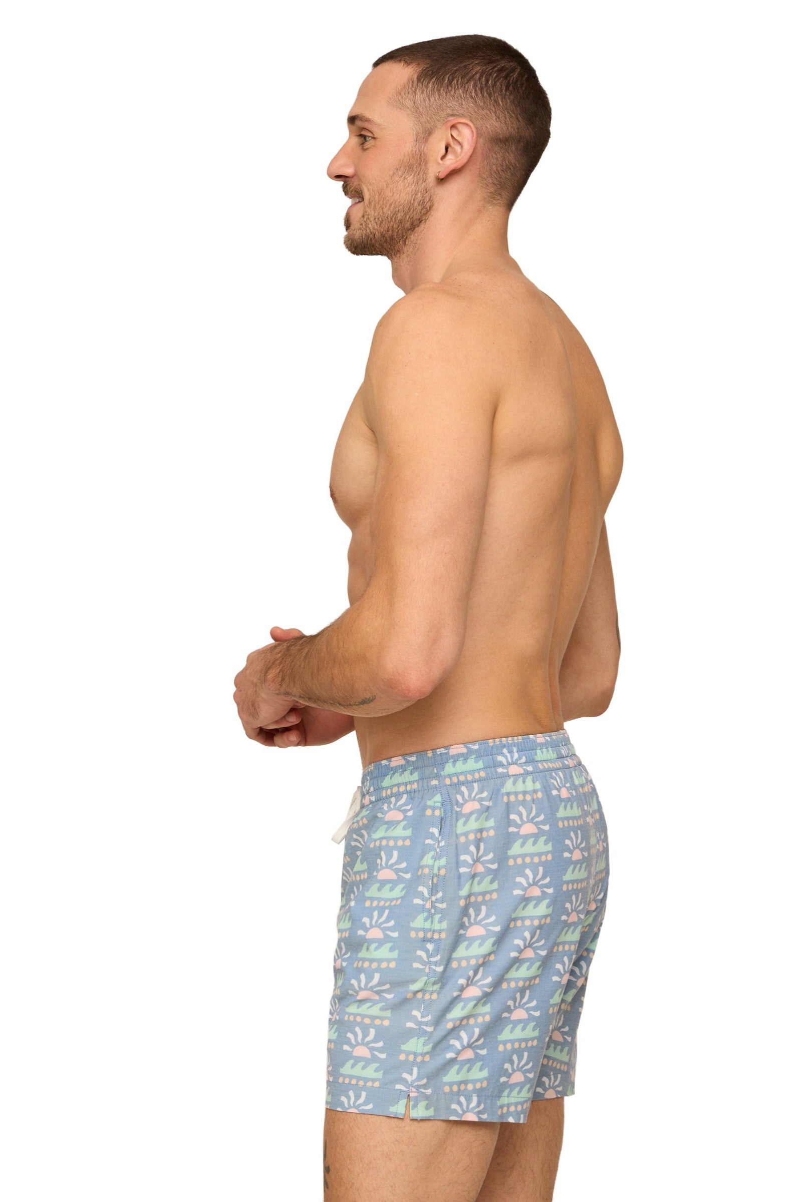 A shirtless man stands in profile facing left, wearing Chubbies' The Easygoers 5.5 Inch Lined Swim shorts with a white drawstring, set against a plain white background.