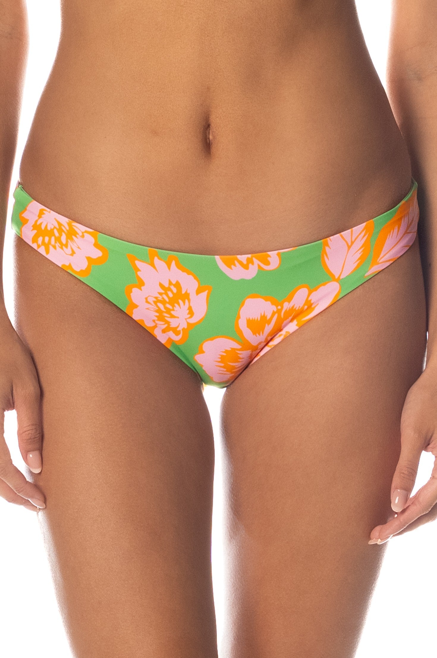 A person is shown from mid-torso to upper thighs, wearing the Maaji Sunset Petals Iconic Bottom in SUNSET PETALS, featuring a green high-rise design with a pink and orange floral pattern against a white background. These reversible swimwear bottoms offer classic coverage and versatile style.