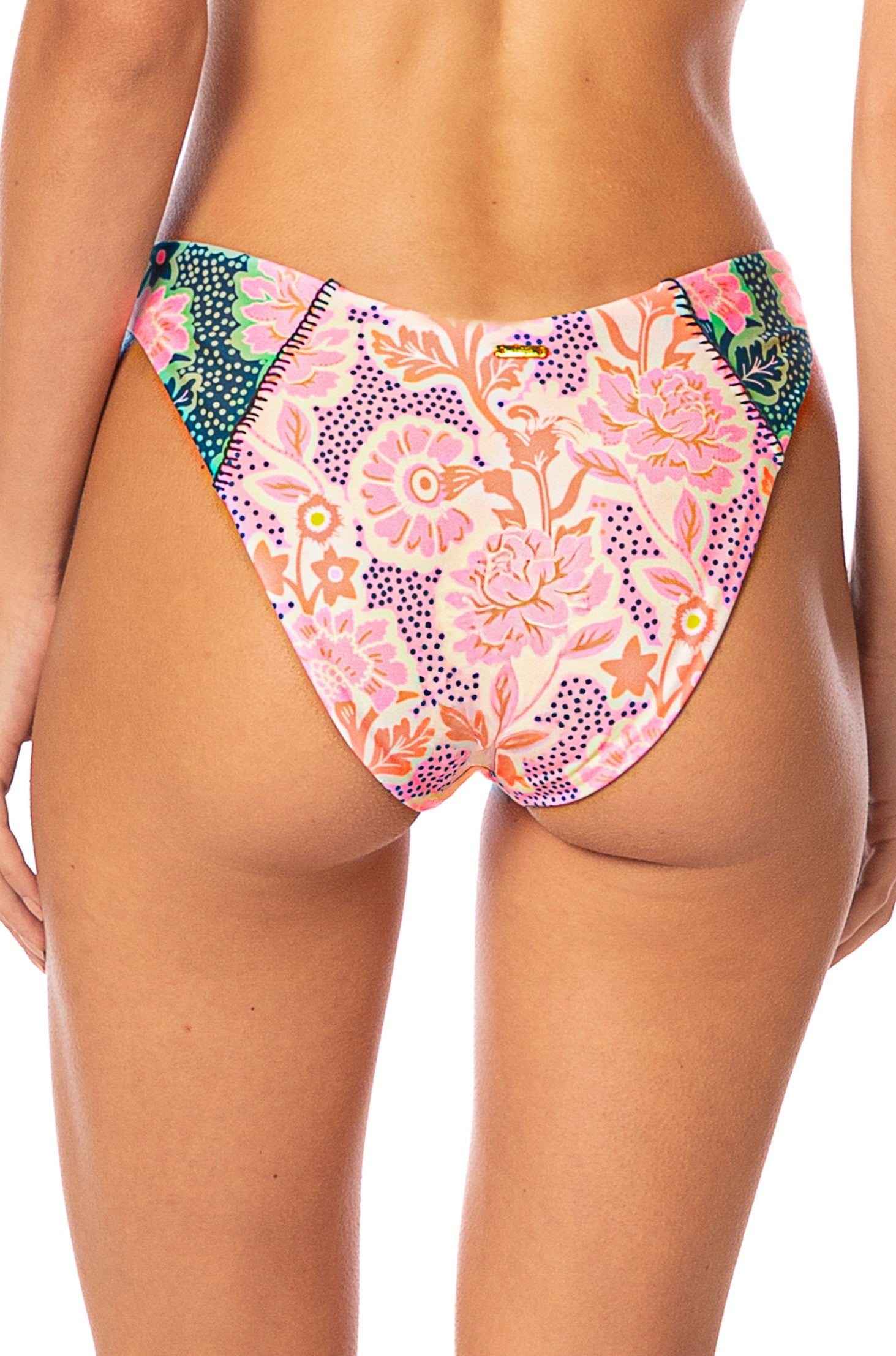 A person is shown from the waist down, wearing the Maaji Blush Floral Splendour Bottom, a high-waisted bikini bottom featuring a colorful floral and dotted pattern in pink, orange, green, and purple tones.