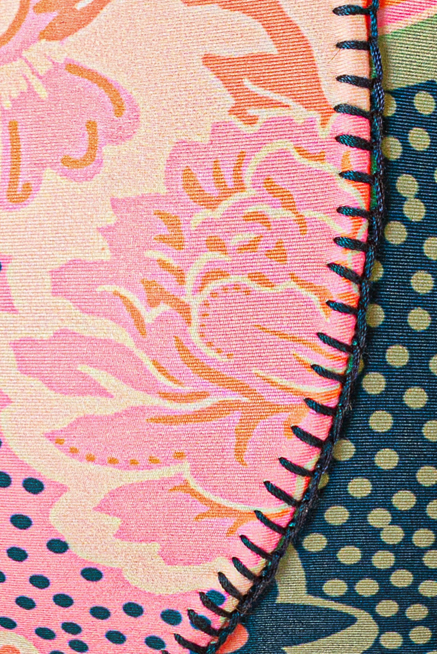 Close-up of Maaji's Blush Floral Splendour Bottom, featuring pink floral fabric with decorative stitching, set beside a navy blue section with light green polka dots and finished with a thick dark edge.