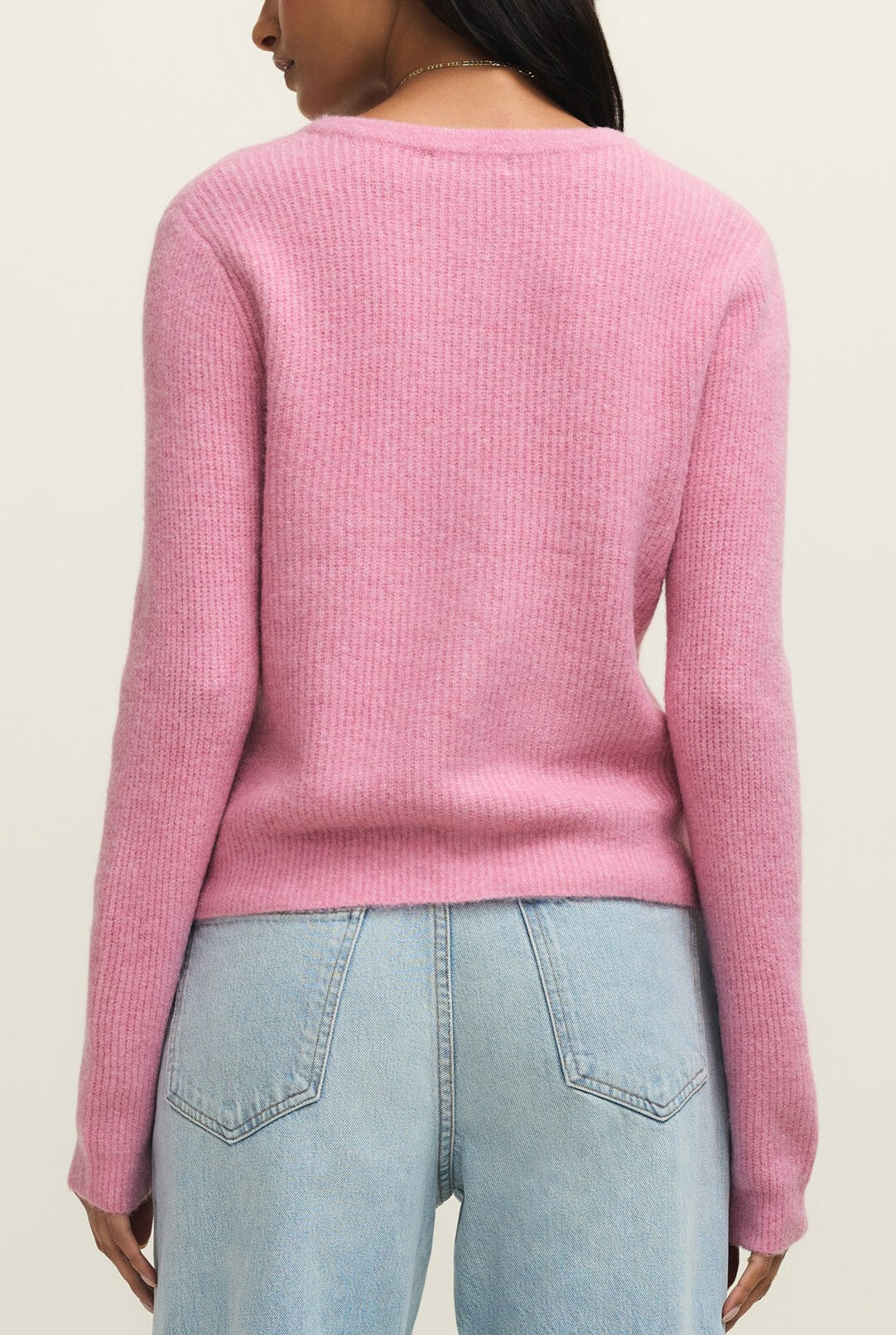 A person wearing the Z Supply Medina Rib Cardigan in Pink Crush and light blue jeans, shown from the back against a plain light background—perfect for casual layering.