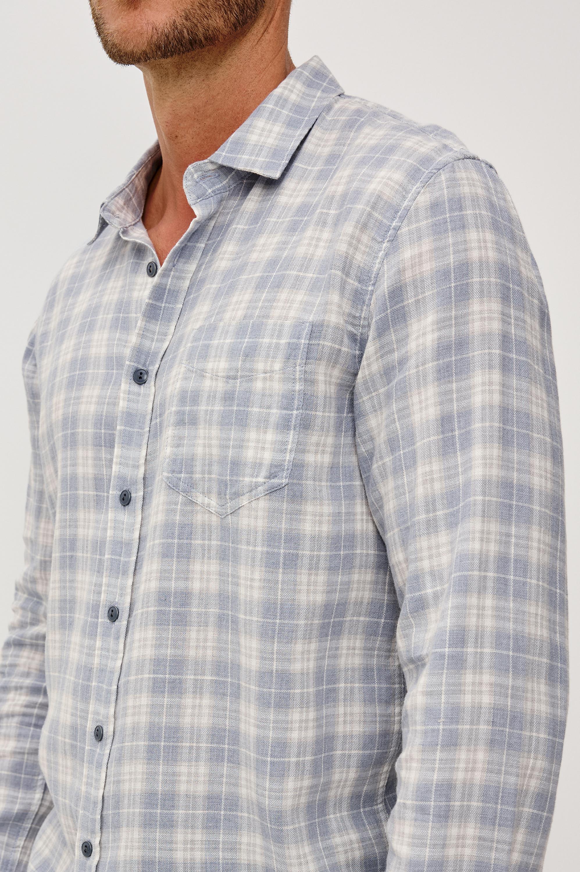 A man wearing the Rails Wyatt Thatch Cloud Cream Plaid Woven shirt, featuring a soft light blue and white plaid pattern and a chest pocket. The photo captures his upper body from the mouth down against a plain background.