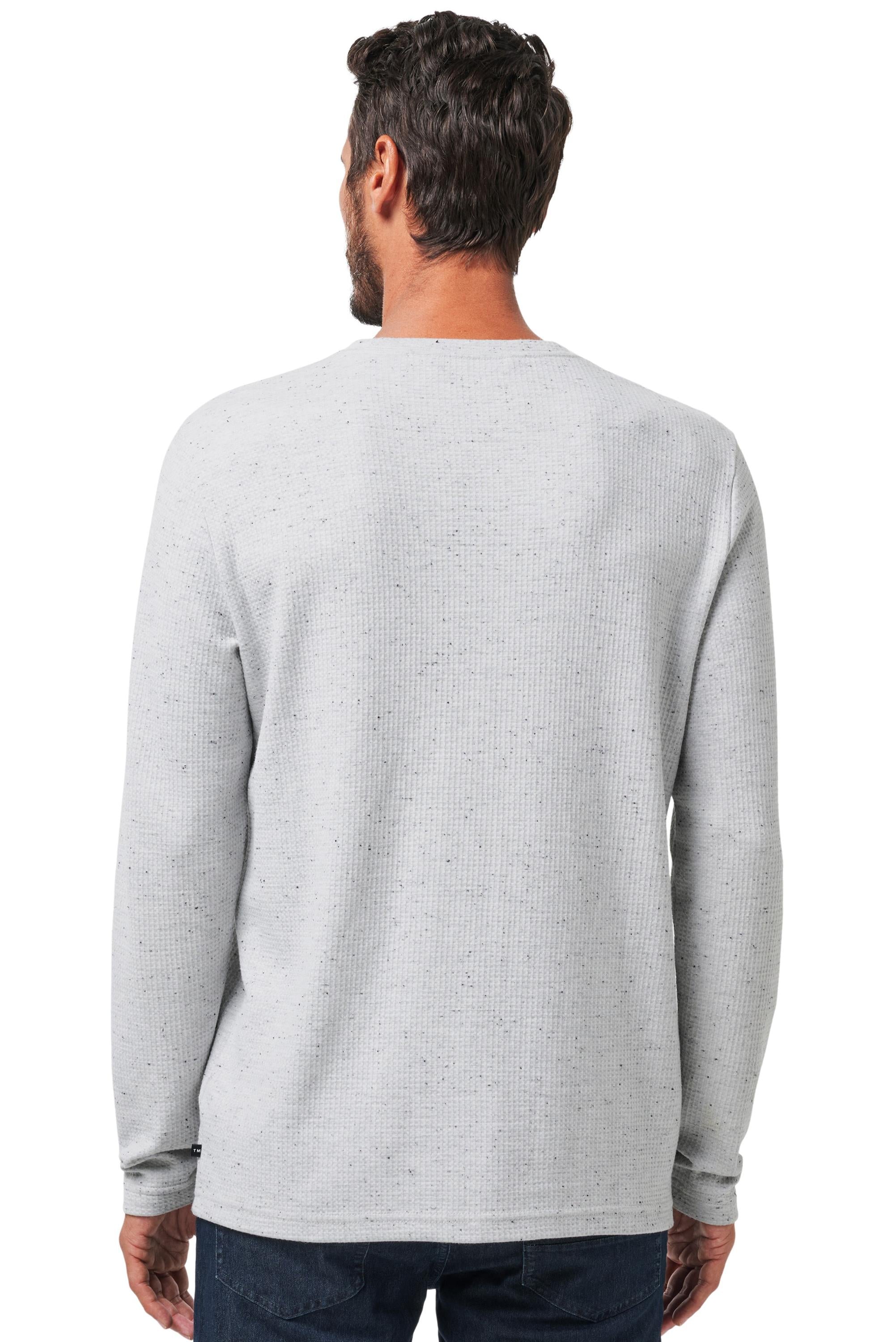 A man with short dark hair, dressed in a light gray TravisMathew Cloud Waffle Crew long-sleeve shirt and dark jeans, is shown from the back against a white background.