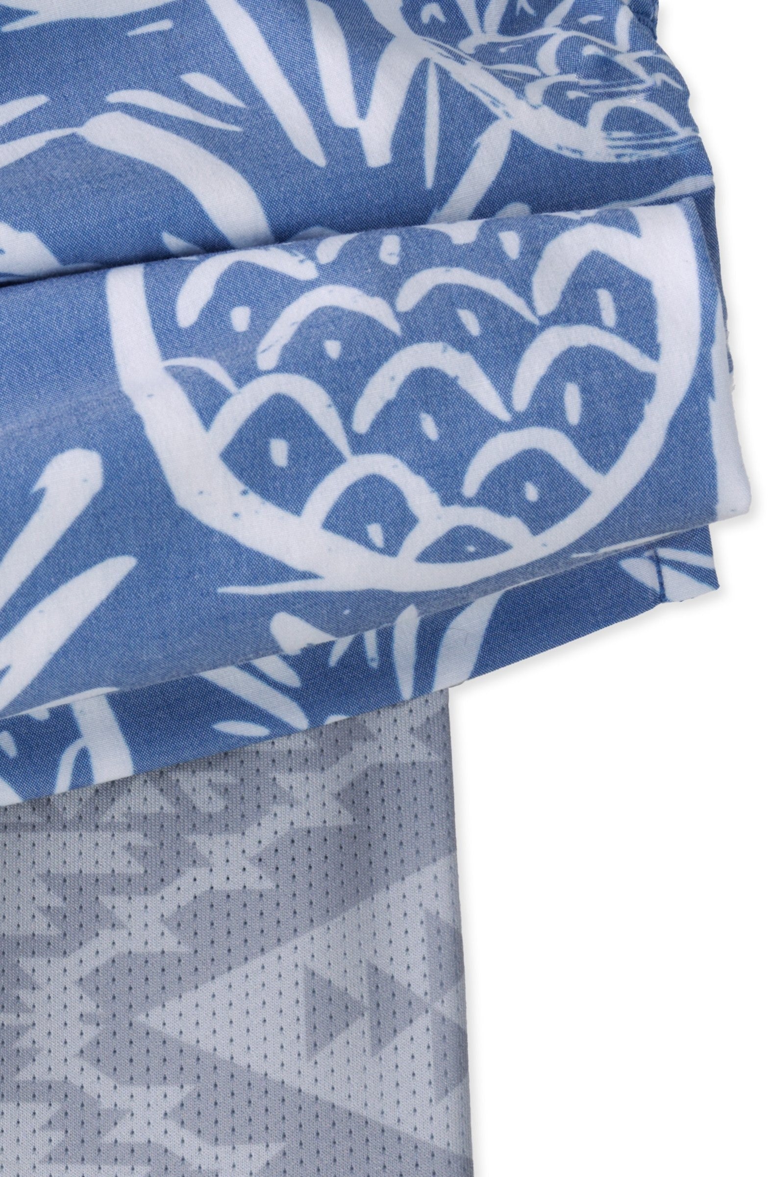 Close-up of The Thighnapples 5.5 Inch Lined Swim by Chubbies: folded blue and white fabric with bold, abstract circular and leaf-like patterns, featuring four-way stretch and subtle geometric designs for comfort.