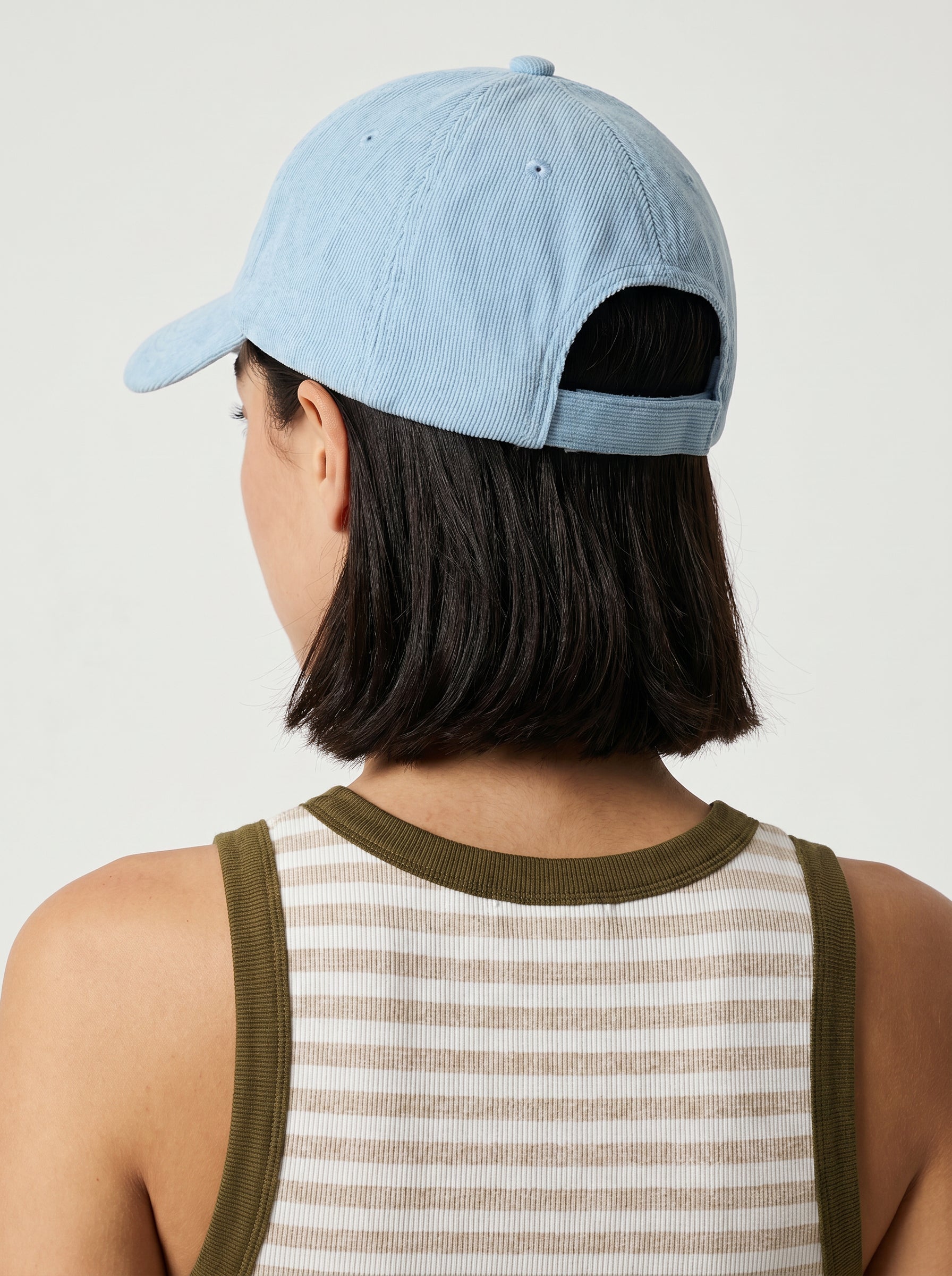 A person with short dark hair, seen from behind against a plain background, wears the South Moon Under Margarita Time Denim Hat—a light blue baseball cap with an adjustable strap—and a sleeveless ribbed top with green trim.