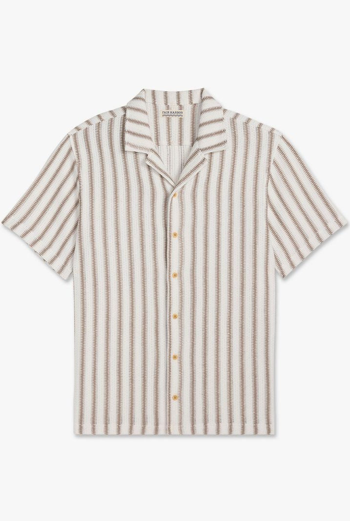The Fair Harbor Waveloom Crochet Shirt is a short-sleeved, button-up organic cotton shirt with a camp collar, relaxed fit, and vertical beige and white stripes, shown on a white background.