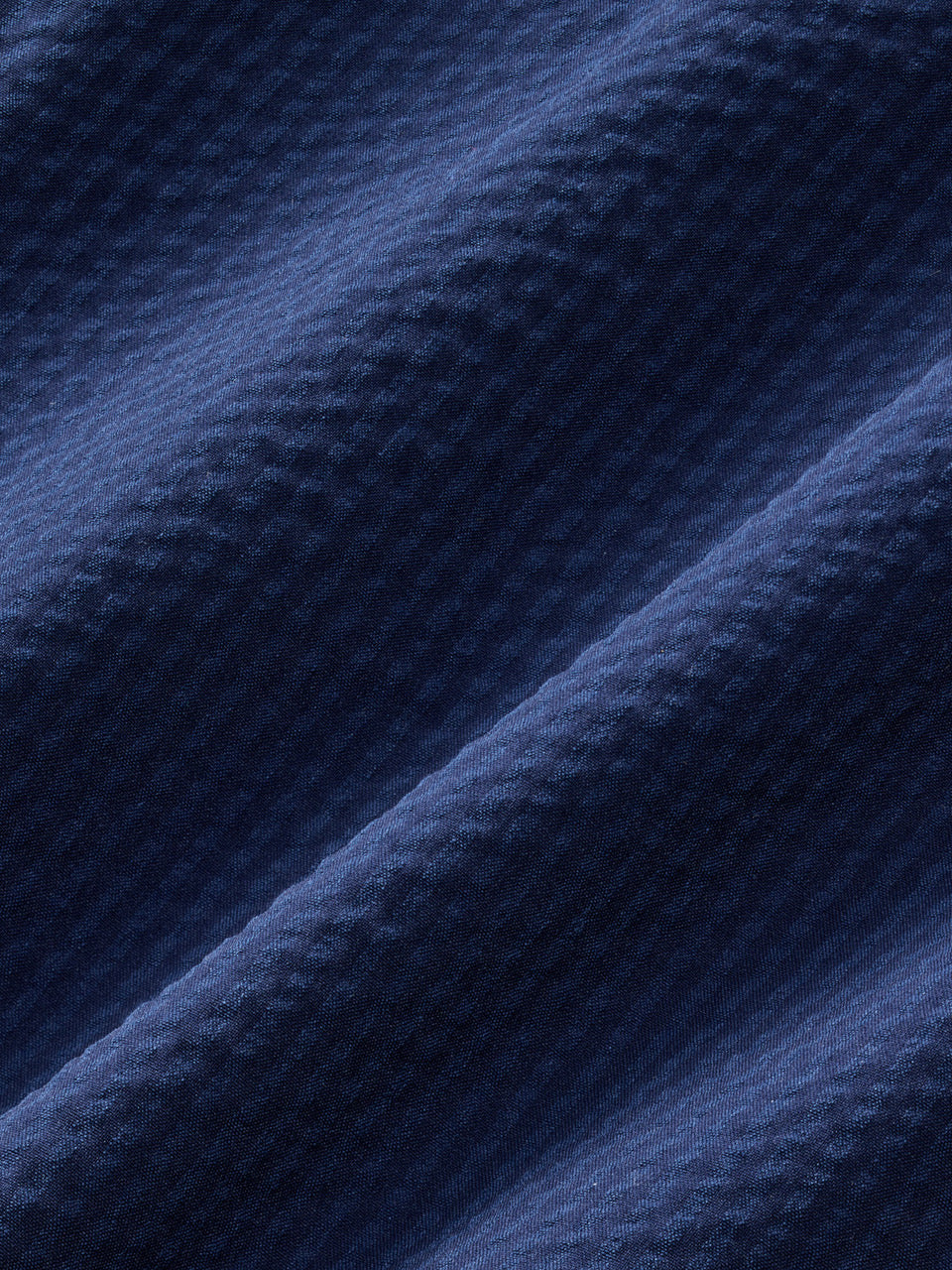 Close-up of Fair Harbor’s Bayberry Trunk 7 Inch in Navy Seersucker, featuring dark blue recycled polyester fabric with a ribbed, wavy seersucker pattern and subtle diagonal ridges.